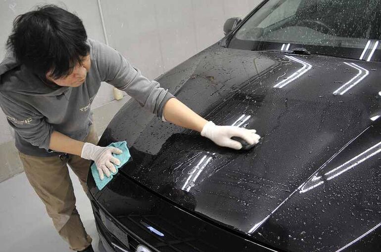 ボルボV60のボディに付着した鉄粉をトラップ粘土で除去している写真