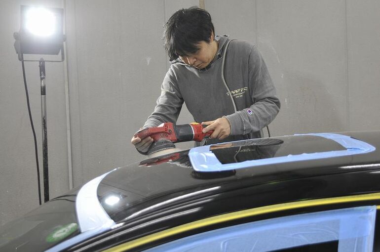 ボルボV60のルーフ部をライトを当てて磨いている写真